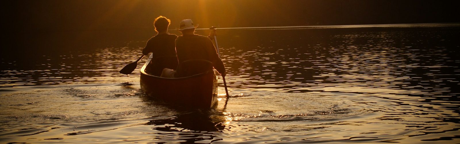 men rowing boat during sunset